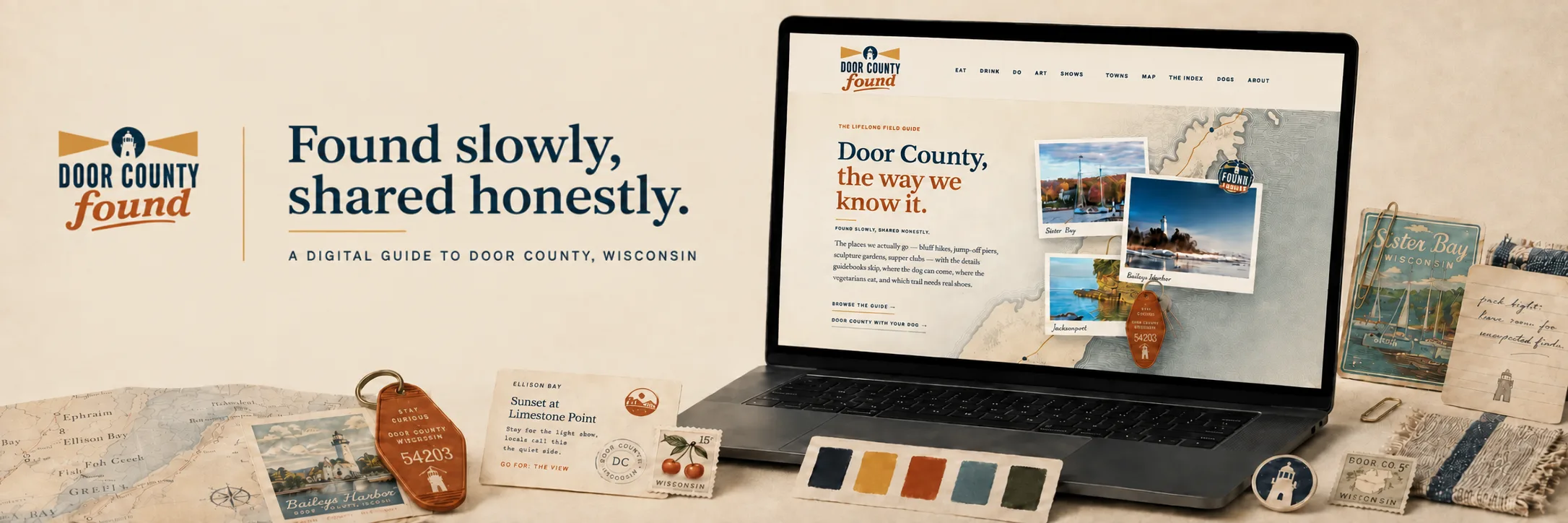 The Door County Found identity laid out flat: at left the Door County Found logo &mdash; a white lighthouse in a navy disc, gold beams spreading either side of it, the name in navy capitals above the word &ldquo;found&rdquo; underlined in rust script &mdash; then the headline &ldquo;Found slowly, shared honestly.&rdquo; and beneath it &ldquo;a digital guide to Door County, Wisconsin.&rdquo; At right a laptop stands open on the site&rsquo;s front page &mdash; &ldquo;Door County, the way we know it,&rdquo; a drawn map of the peninsula, and pinned polaroids of Sister Bay, Baileys Harbor and Jacksonport. Around it on cream paper: a folded nautical chart of the shoreline, a Baileys Harbor lighthouse postcard, a leather motel keyfob stamped &ldquo;stay curious,&rdquo; a fifteen-cent cherry stamp, a strip of five cloth swatches in navy, gold, rust, teal and green, and a handwritten note reading &ldquo;pack light, leave room for unexpected finds.&rdquo;