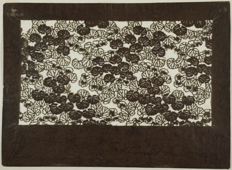 A dark paper stencil cut with an even carpet of mallow leaves, some solid and some open.