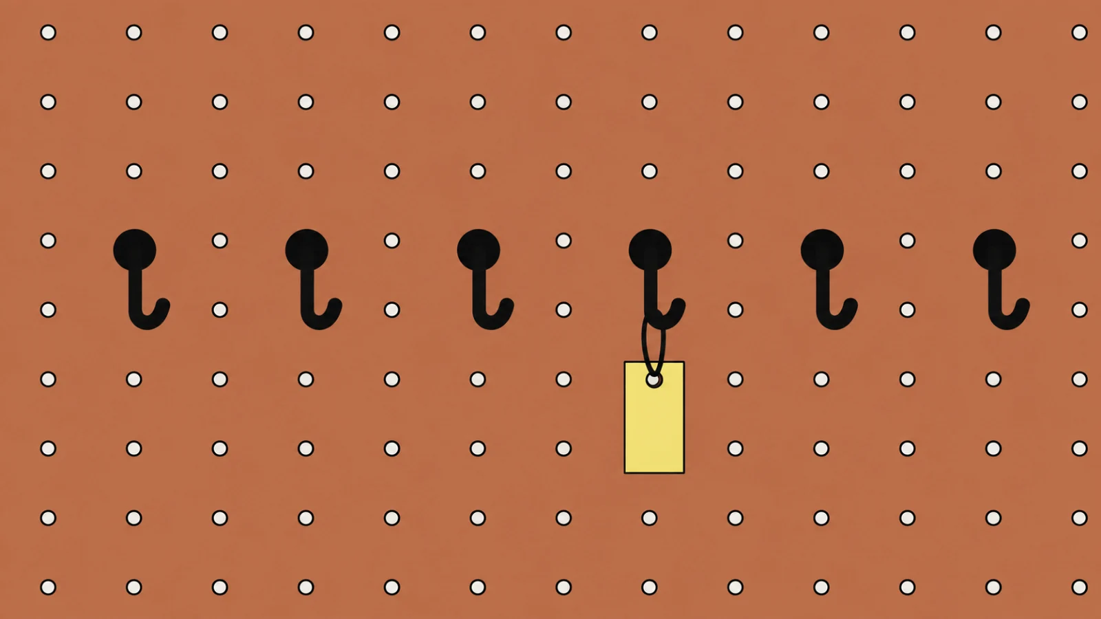A large terracotta pegboard cropped by the frame, a straight row of six black hooks across its middle, five of them empty and the fourth holding one small butter-yellow tag.